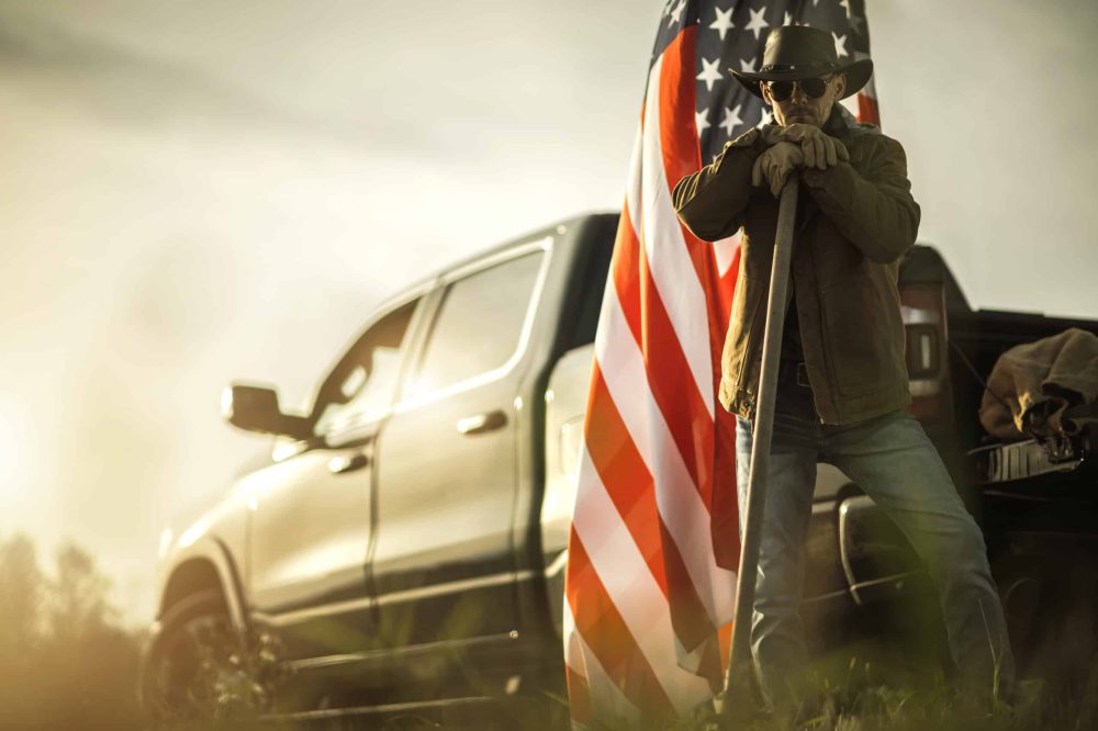 Caucasian American Patriot Cowboy Farmer Staying  in Front of His Pickup Truck and American National Flag